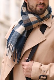 Smiling man in warm scarf on blurred background, closeup