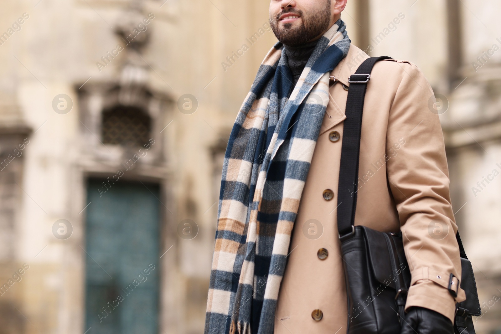 Photo of Smiling man in warm scarf outdoors, closeup. Space for text