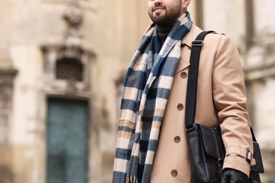 Smiling man in warm scarf outdoors, closeup. Space for text