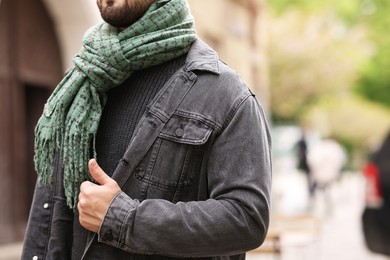 Man in warm scarf on city street, closeup