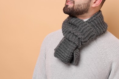 Smiling man in knitted scarf on beige background, closeup. Space for text