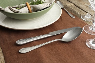 Photo of Stylish setting with cutlery, glasses, plate and bowl on wooden table, closeup
