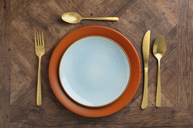 Photo of Stylish setting with cutlery and plates on wooden table, flat lay