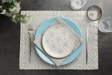 Stylish setting with cutlery, glasses and plates on black table, flat lay