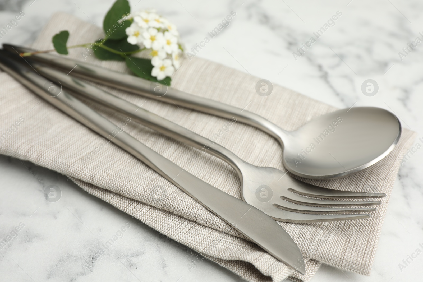 Photo of Stylish setting with cutlery and napkin on white marble table, closeup