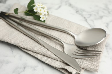 Photo of Stylish setting with cutlery and napkin on white marble table, closeup