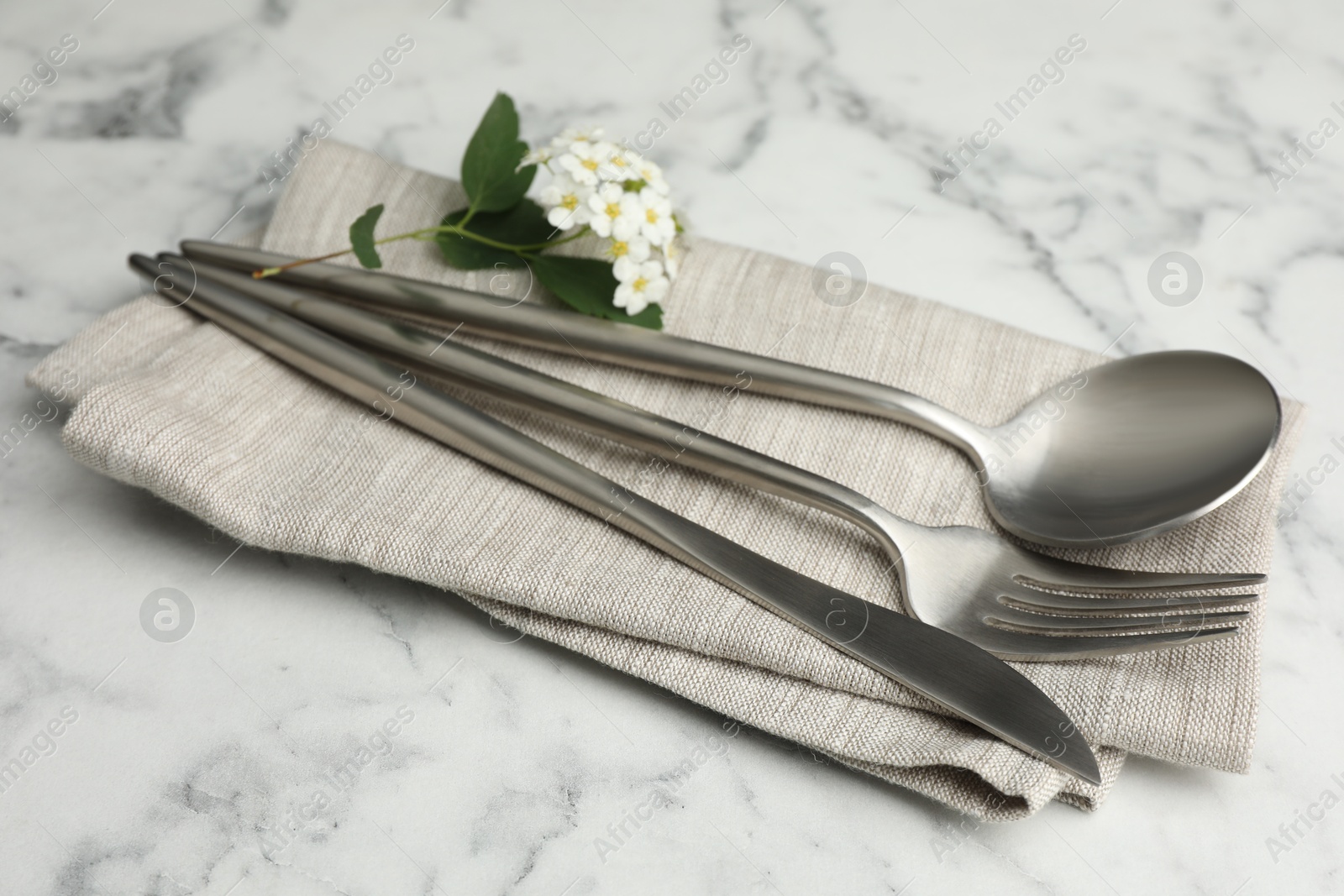 Photo of Stylish setting with cutlery and napkin on white marble table