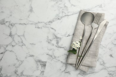 Stylish setting with cutlery and napkin on white marble table, top view. Space for text