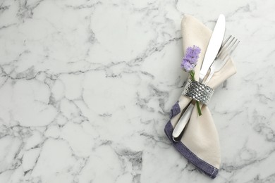 Photo of Stylish setting with cutlery and napkin on white marble table, top view. Space for text