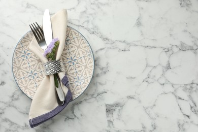 Photo of Stylish setting with cutlery and plate on white marble table, top view. Space for text