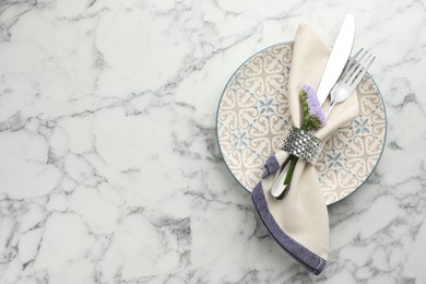 Stylish setting with cutlery and plate on white marble table, top view. Space for text