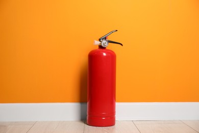 Fire extinguisher on floor near orange wall