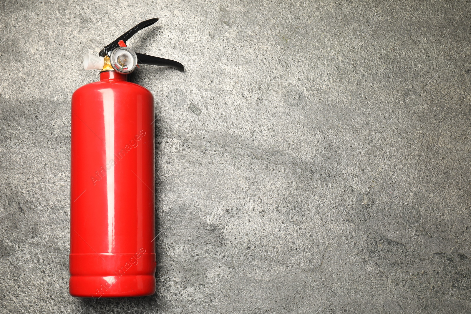 Photo of One red fire extinguisher on gray textured background, top view. Space for text