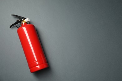 Photo of One red fire extinguisher on gray background, top view. Space for text