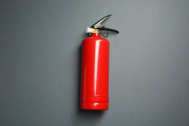 Photo of One red fire extinguisher on gray background, top view