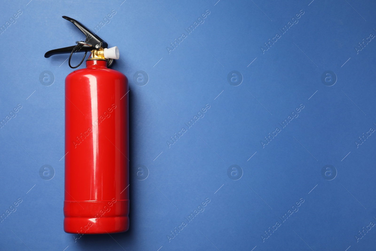 Photo of One red fire extinguisher on blue background, top view. Space for text