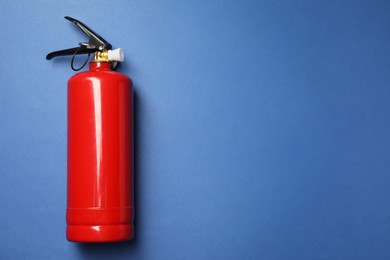 Photo of One red fire extinguisher on blue background, top view. Space for text