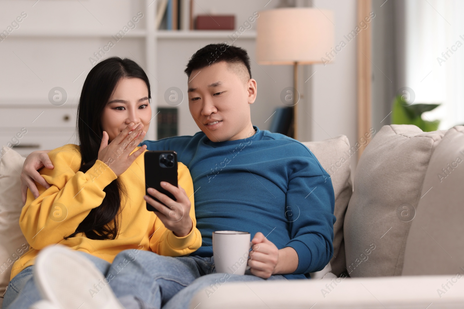 Photo of Happy couple with smartphone on sofa at home