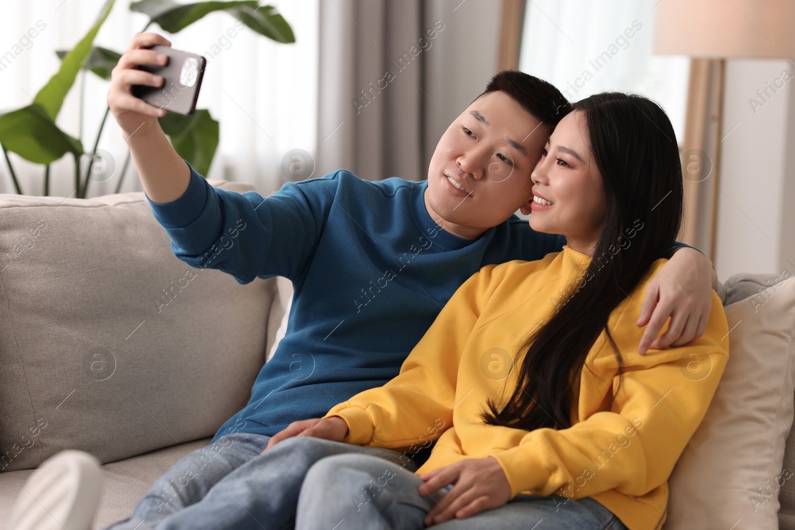 Photo of Happy couple taking selfie on sofa at home