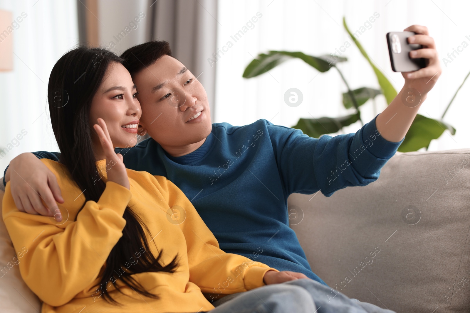 Photo of Happy couple taking selfie on sofa at home