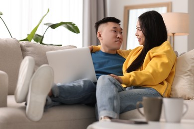 Happy couple with laptop on sofa at home