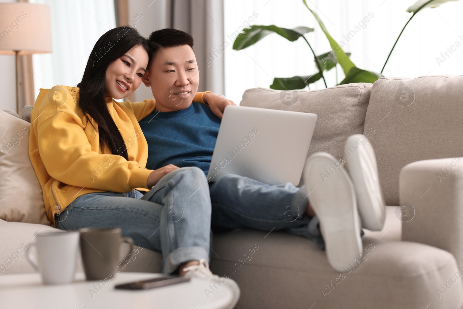 Photo of Happy couple with laptop on sofa at home