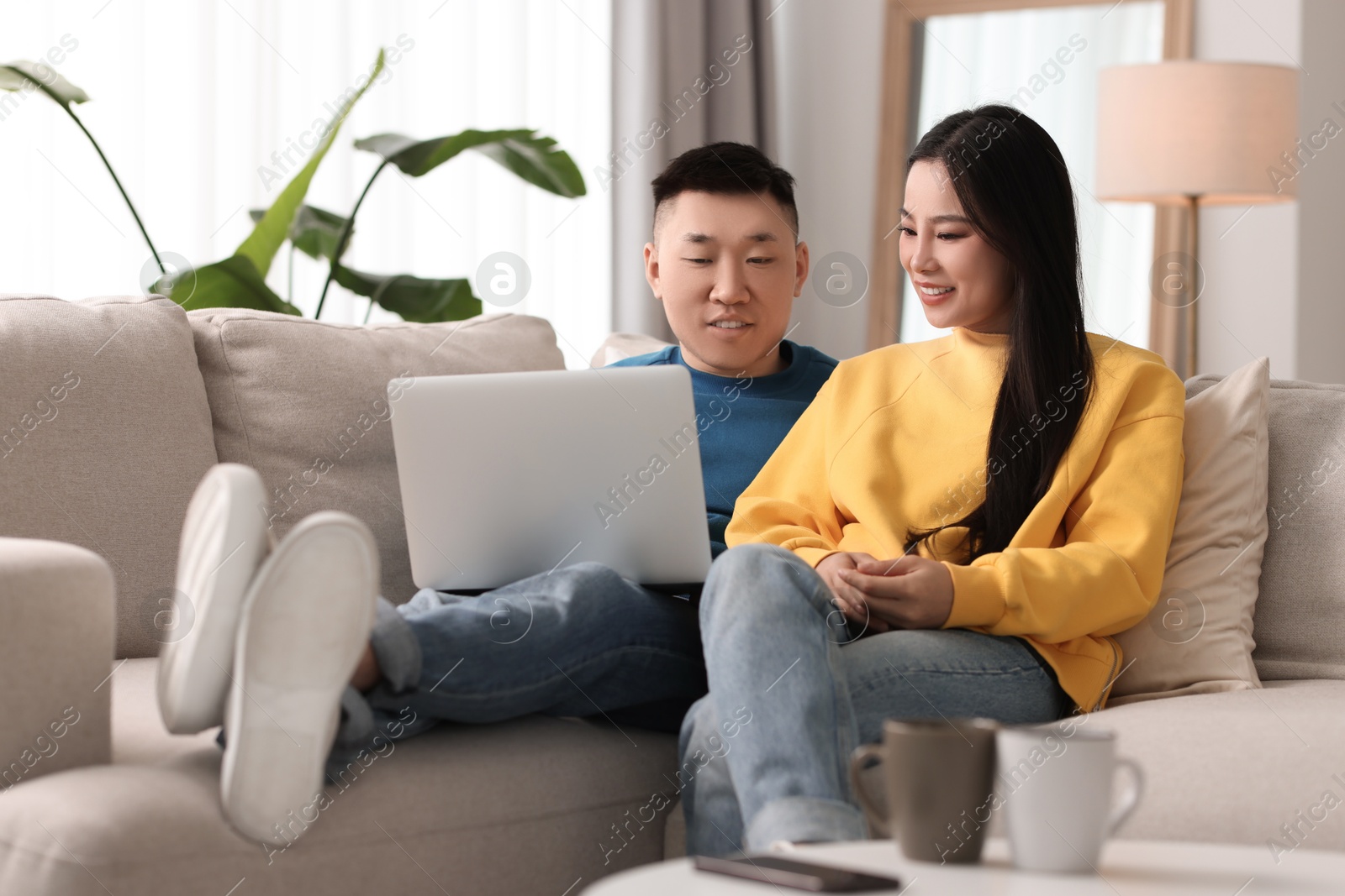 Photo of Happy couple with laptop on sofa at home