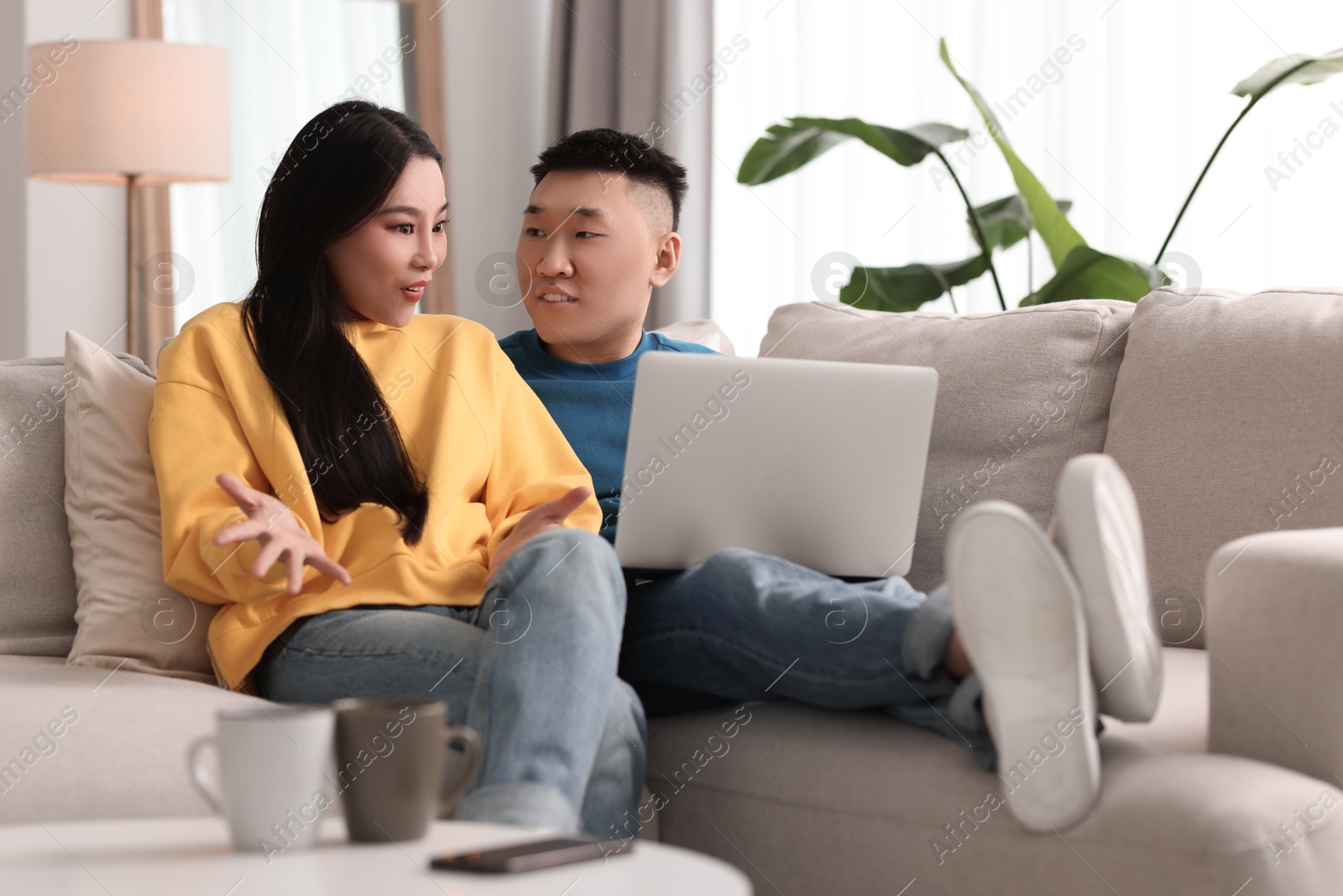 Photo of Happy couple with laptop on sofa at home