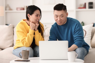 Happy couple spending time together and using laptop at home