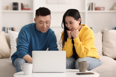 Photo of Happy couple spending time together and using laptop at home