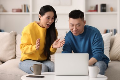 Photo of Happy couple spending time together and using laptop at home