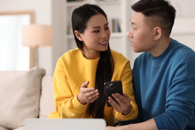 Photo of Happy couple with smartphone on sofa at home