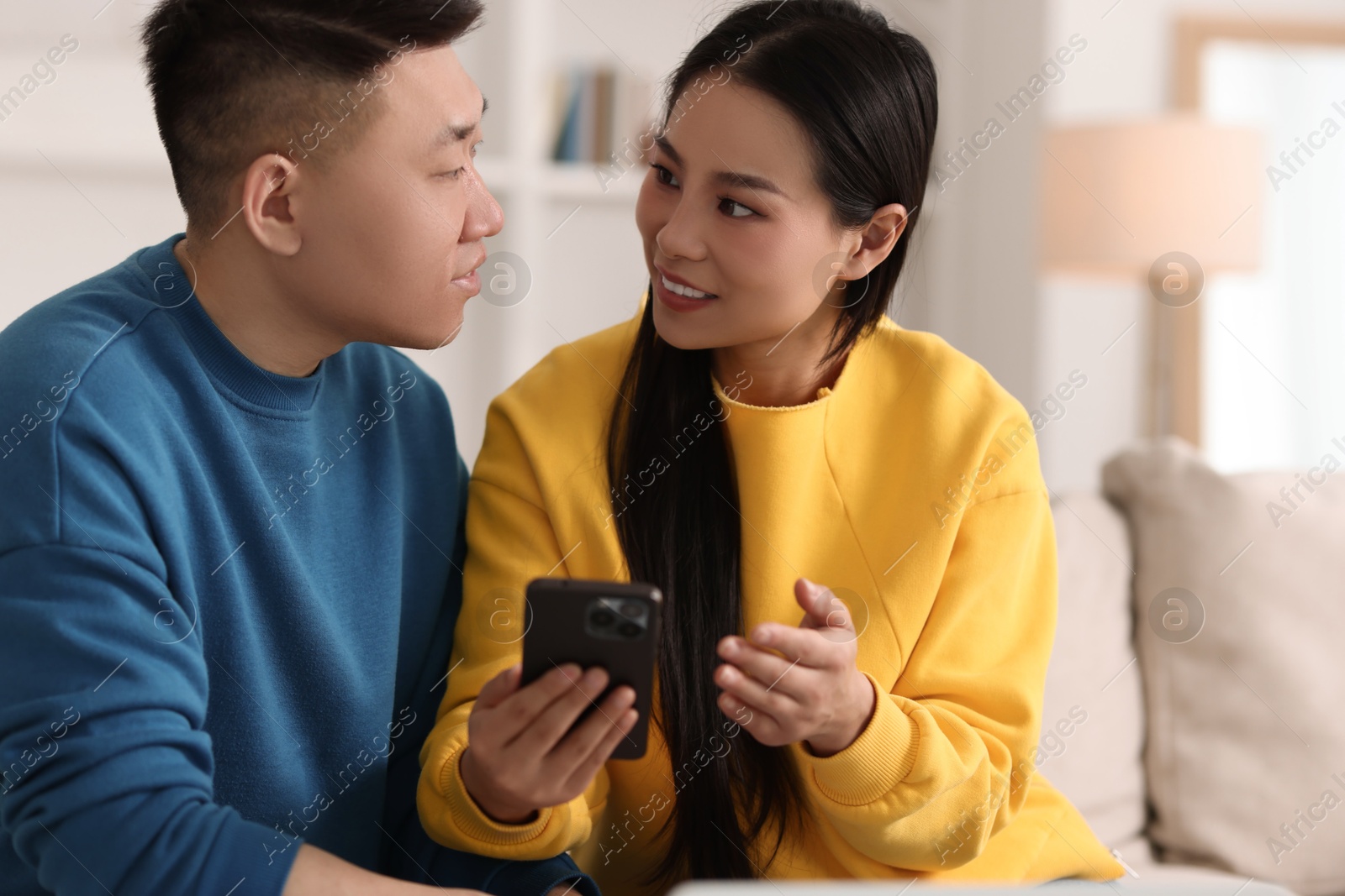 Photo of Happy couple with smartphone on sofa at home