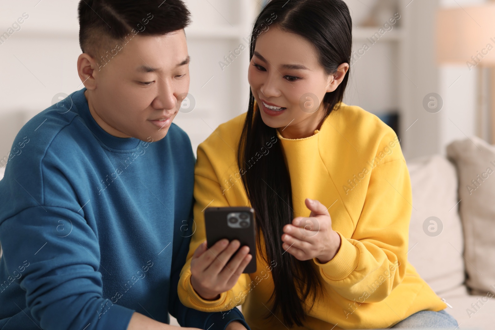 Photo of Happy couple with smartphone on sofa at home