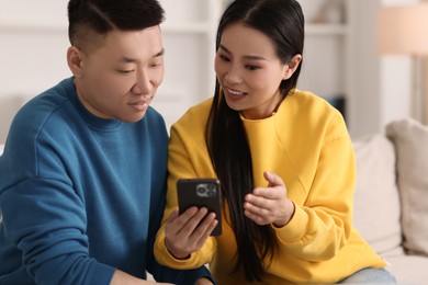 Photo of Happy couple with smartphone on sofa at home