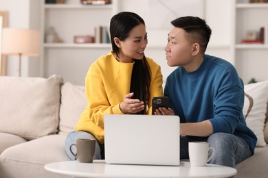 Happy couple with smartphone on sofa at home