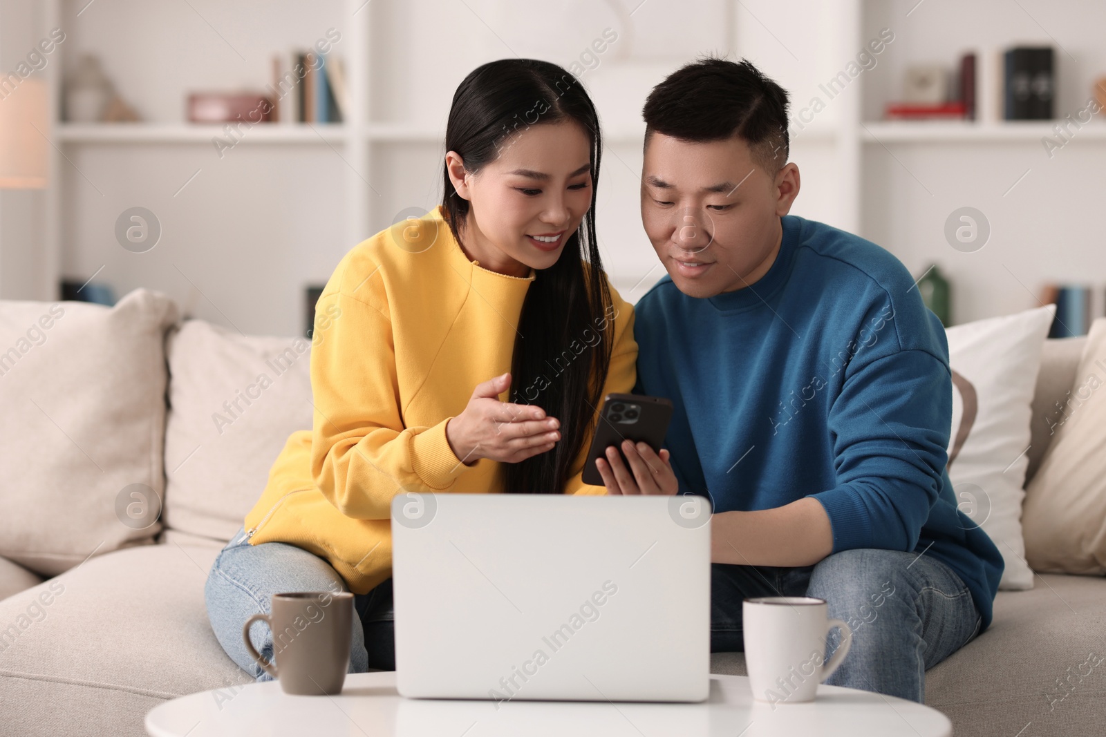 Photo of Happy couple with smartphone on sofa at home