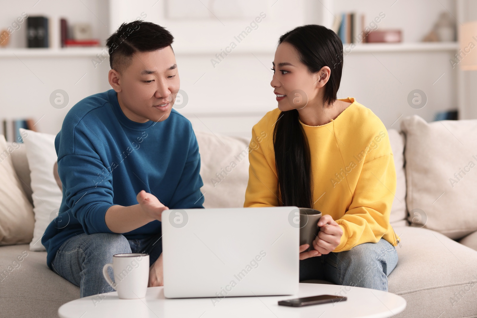 Photo of Happy couple spending time together and using laptop at home