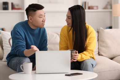 Photo of Happy couple spending time together and using laptop at home