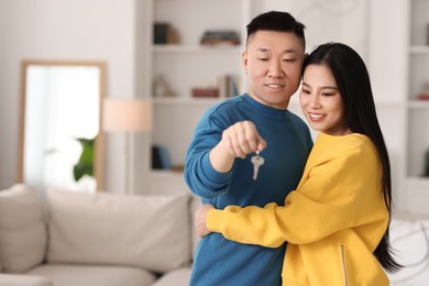 Happy couple with key in their new apartment, space for text