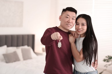 Photo of Happy couple with key in their new apartment, space for text