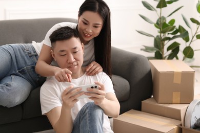 Happy couple with smartphone in their new apartment