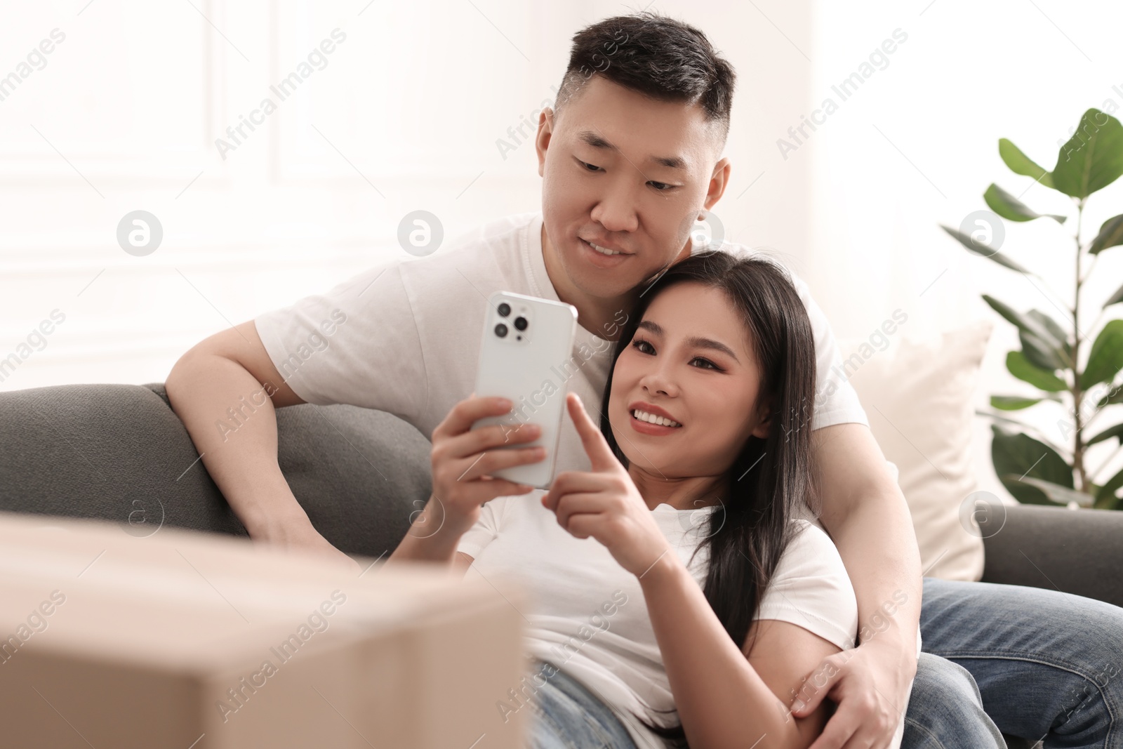 Photo of Happy couple with smartphone in their new apartment