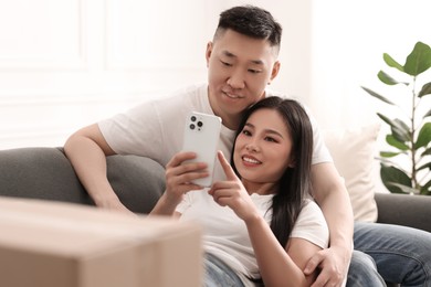 Happy couple with smartphone in their new apartment