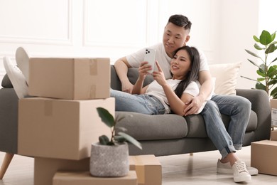 Happy couple with smartphone in their new apartment