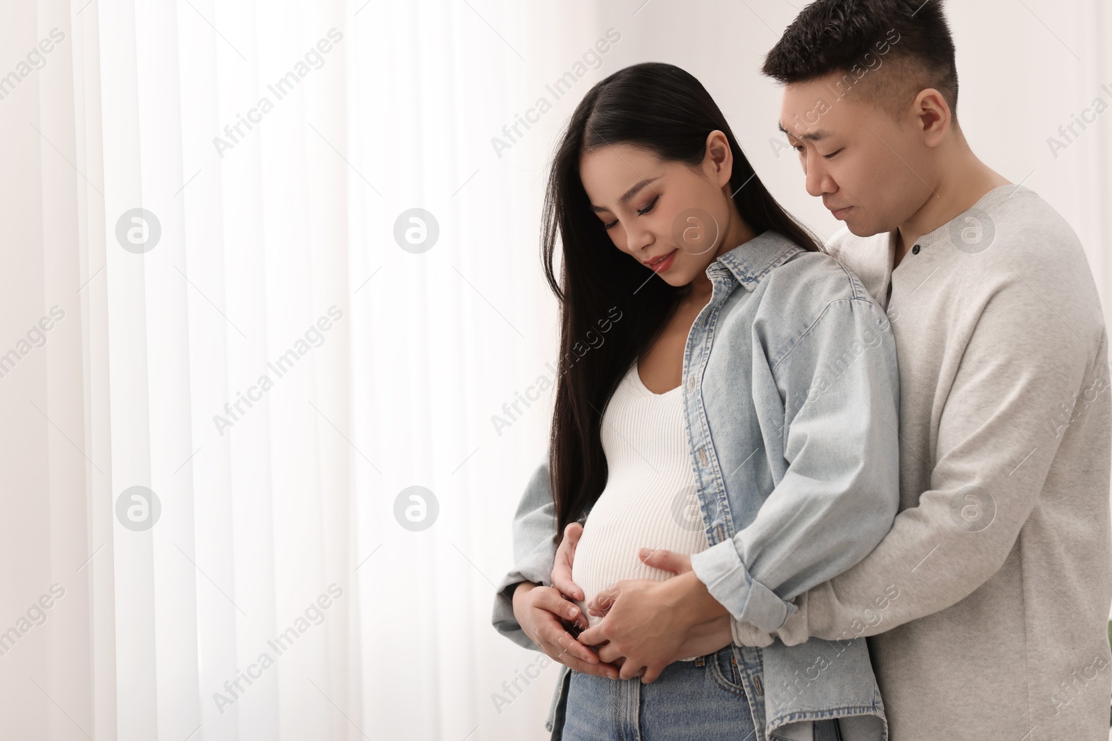 Photo of Man touching his pregnant wife's belly at home, space for text