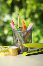 Stapler, holder and other different stationery on white table