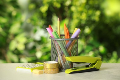 Stapler, holder and other different stationery on white table