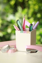 Stapler, holder and other different stationery on white table