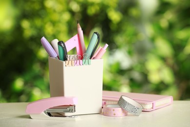 Stapler, holder and other different stationery on white table